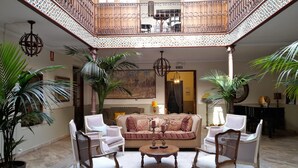 A spacious atrium with a high ceiling, a central seating area with a sofa and chairs, and a balcony with ornate railings. - La Centinela Room, Rural Hotel in Consuegra (Consuegra)