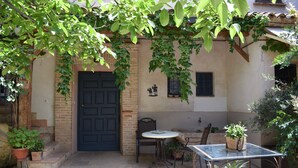 A courtyard with a door, a table, chairs, and potted plants. - Family Room La Hornacina, Hotel Rural Consuegra (Consuegra)