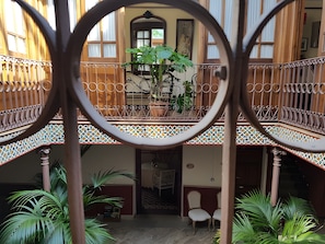 A courtyard with a balcony, potted plants, and a statue. - Room 'Familiar - La Despensa' with Shared Pool, Wi-Fi and Air Conditioning (Consuegra)