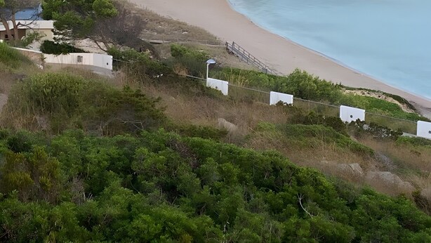 A coastal landscape with a beach, greenery, and buildings in the background. - Gin & Tonic Apartment in Son Parc with Pool, Padel Court, and Sea View near Son Saura Beach (Son Parc)