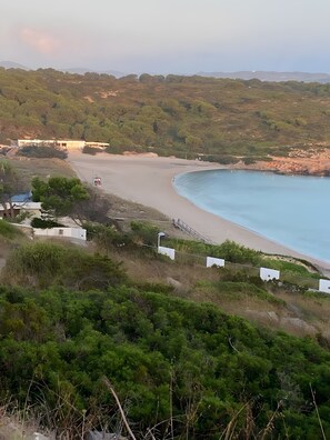 Un paysage côtier avec une plage, de la végétation et des bâtiments en arrière-plan.