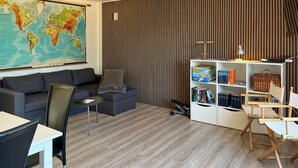 Uma sala de estar com um grande mapa-múndi, um sofá, uma mesa de centro, uma estante de livros e uma escrivaninha com uma cadeira.