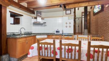 Una cocina con armarios de madera, microondas y comedor con sillas y mesa.