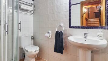 Een badkamer met toilet, wastafel, handdoekhouder en douche.