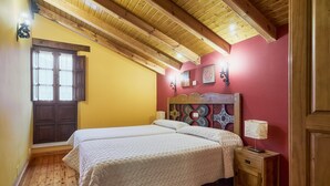 Een slaapkamer met een houten plafond, een bed met hoofdeinde, een nachtkastje en een raam met luiken.