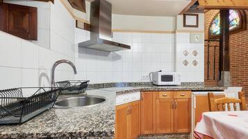 Una cocina con encimeras de granito, armarios de madera, un lavamanos de acero inoxidable, un microondas y una estufa.