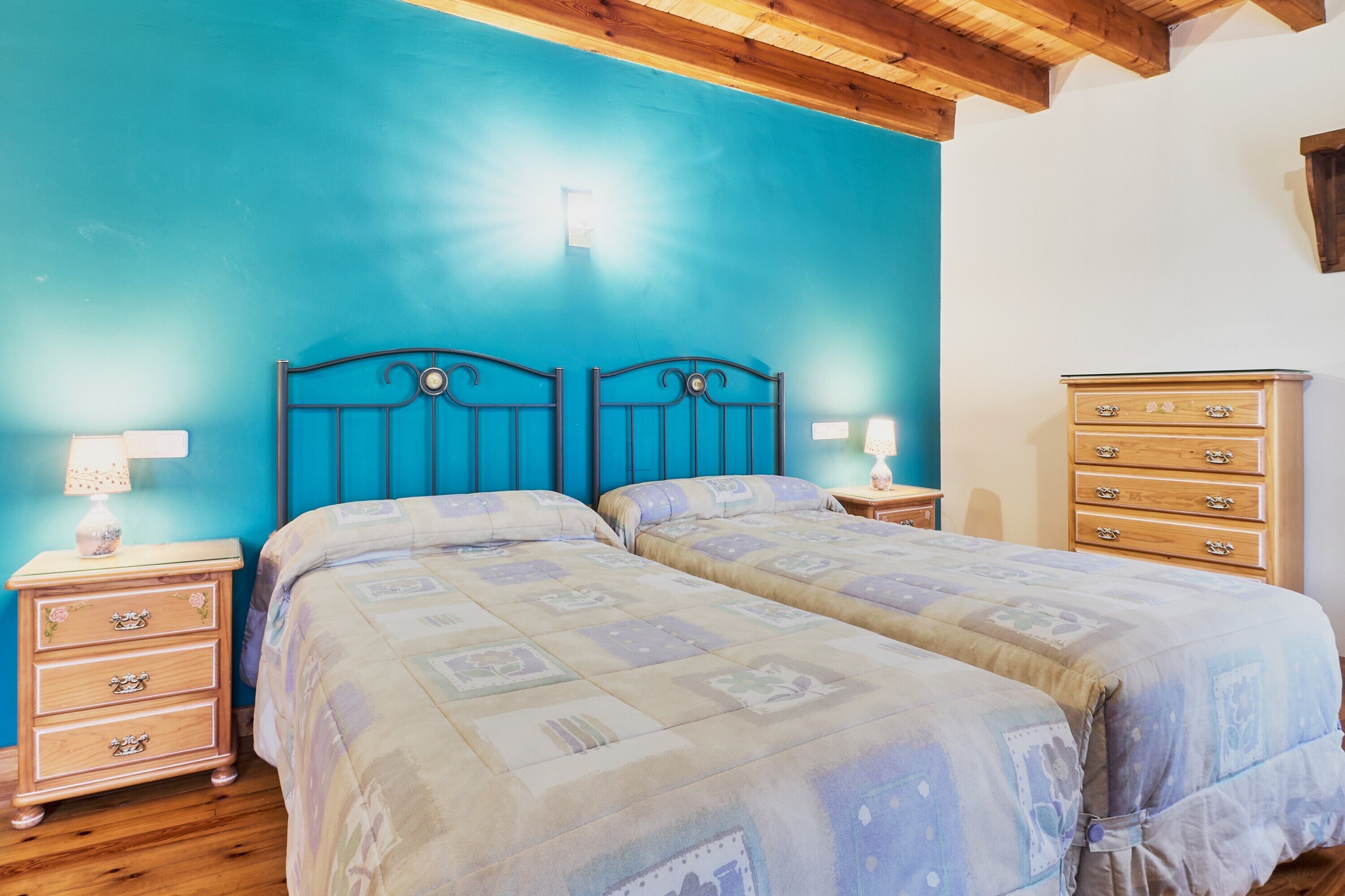 A bedroom with two beds, a wooden dresser, and a nightstand with a lamp.