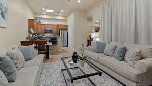 A spacious living room with a sofa, coffee table, and a dining area with chairs and a table. - Desert Haven Townhome – Comfort, Style & Prime Tubac Location (Tubac)