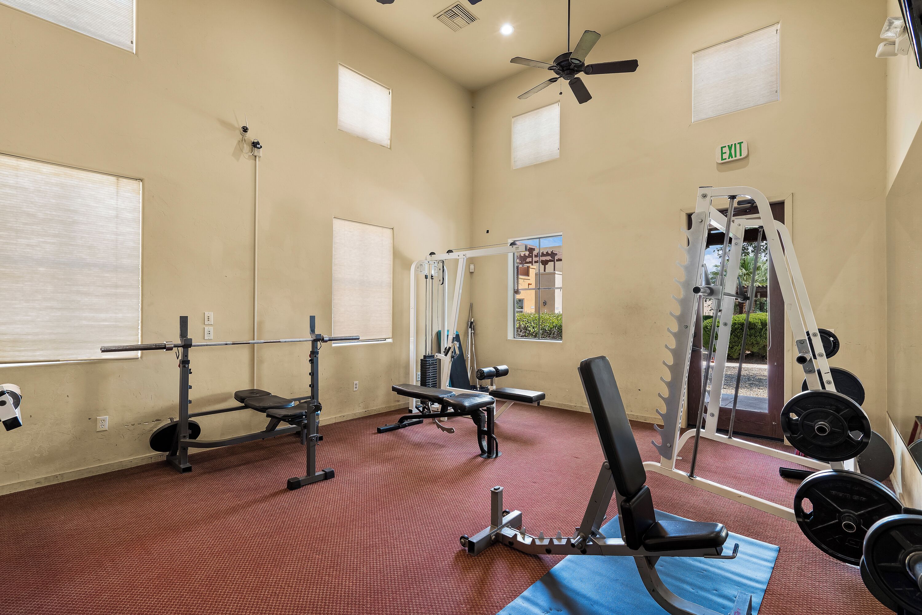 A gym with various exercise equipment, including a bench press, squat rack, and weight bench.