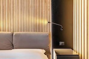 Une chambre d’hôtel moderne, équipée d’un lit, d’une table de chevet et d’un mur recouvert de lambris en bois verticaux.