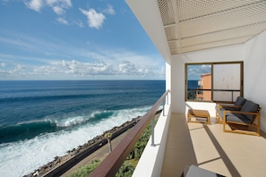 Un balcone con vista sull'oceano, una panchina di legno e un divano.