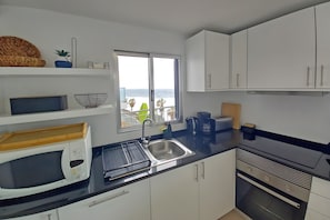Una cucina moderna con vista sul mare, dotata di forno a microonde, bollitore e lavello.