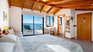 Een slaapkamer met een groot bed, een bureau en uitzicht op zee.