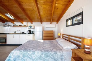 A bedroom with a bed, bedside lamp, wooden headboard, and a window. - Apartment 'The Wave House  - Oceanfront' with Sea View, Wi-Fi and Air Conditioning (Jardim do Mar)