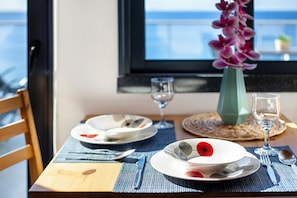 A dining table set with plates, cutlery, and a vase of flowers. - Apartment 'The Wave House  - Oceanfront' with Sea View, Wi-Fi and Air Conditioning (Jardim do Mar)