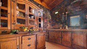 Une cuisine avec des meubles en bois, un mur en pierre et une fenêtre.