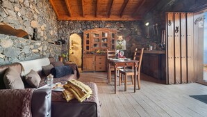 Un intérieur rustique avec des murs en pierre, des meubles en bois, un coin repas et une cuisine.