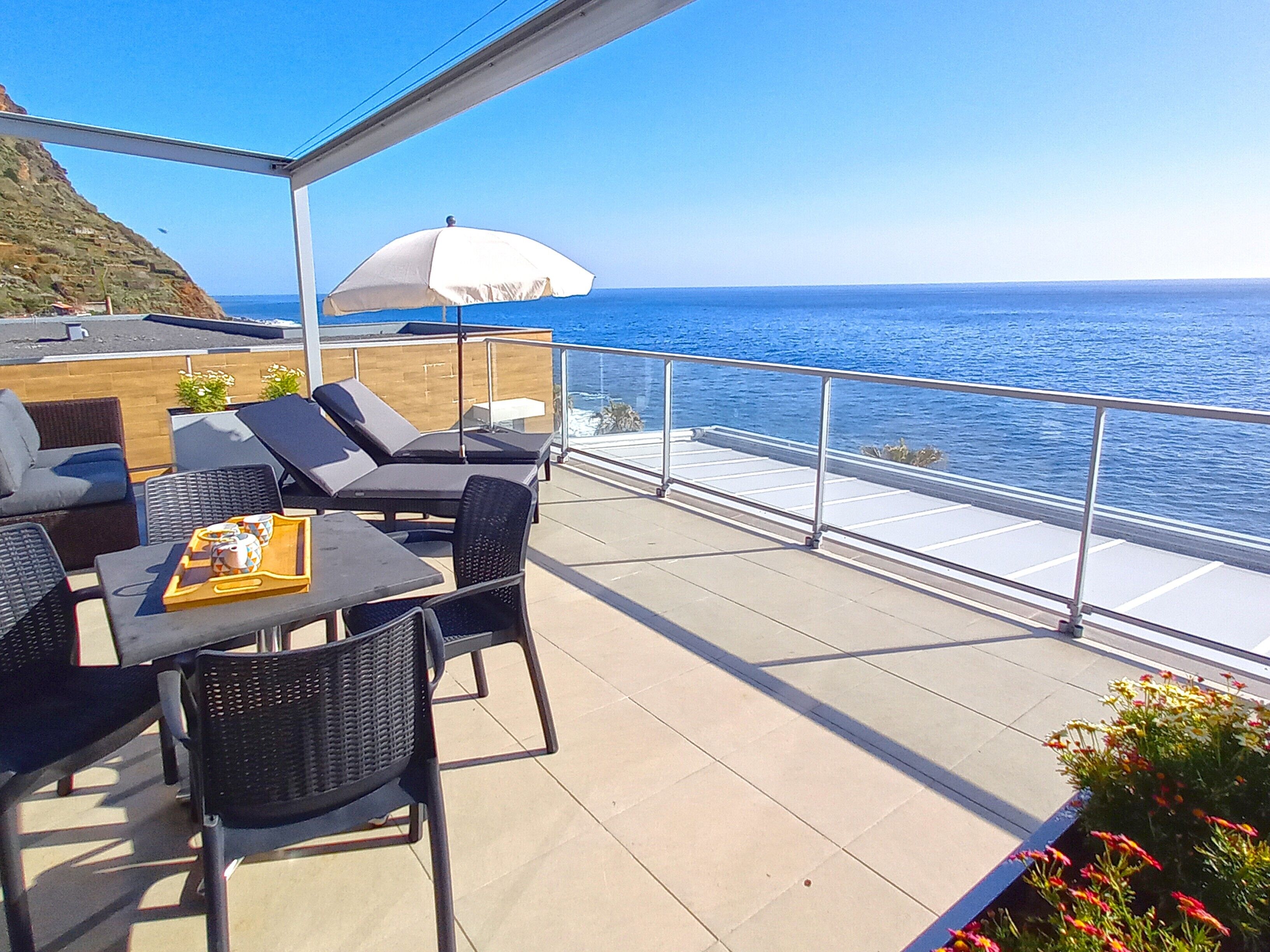 A terrace with outdoor seating, a table with a tray, and a white umbrella.