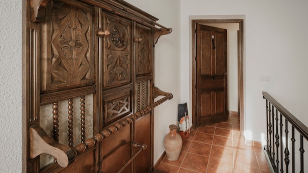 A wooden staircase with a handrail, a vase, and a door at the top.