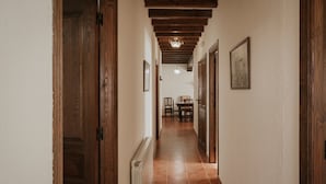 A hallway with wooden doors, a radiator, and a dining area in the distance.