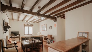 A dining area with a wooden table and chairs, a TV, and a chandelier.