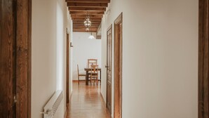 Un couloir avec des portes en bois, un coin repas avec une table et des chaises, et un luminaire suspendu.