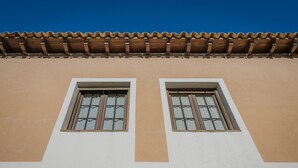 Une façade d ’immeuble avec deux fenêtres, un toit recouvert de tuiles et un mur sobre.