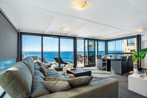 Een moderne woonkamer met een grote bank, een salontafel en een eethoek met stoelen en een tafel.