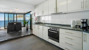 A modern kitchen with white cabinets, a stainless steel oven, and a coffee maker. - Apartment 'The Wave House - Seaside Haven' with Sea View, Wi-Fi and Air Conditioning (Jardim do Mar)