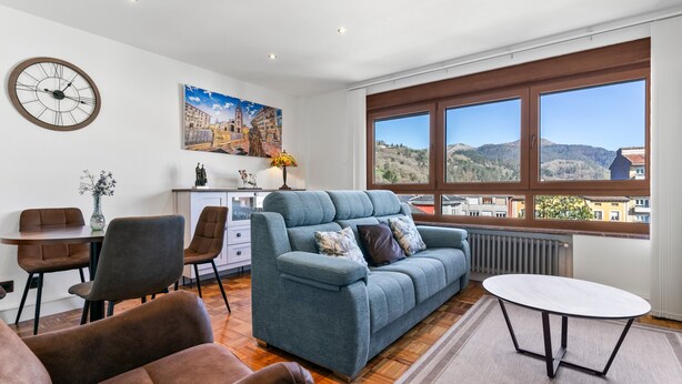 A modern living room with a sofa, chairs, a dining table, a clock, and a painting. - Apartment 'Comarca Del Sella' with Mountain View and Wi-Fi (Arriondas)