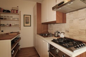 A kitchen with white cabinets, a stainless steel stove, and a tiled backsplash. - Apartment 'Bella' with Mountain View and Wi-Fi (Polpenazze del Garda)