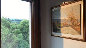 Una ventana con vista a una carretera y árboles, y un cuadro enmarcado en la pared.