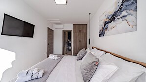Una habitación de hotel moderna con dos camas, un televisor montado en la pared y una obra de arte de mármol.