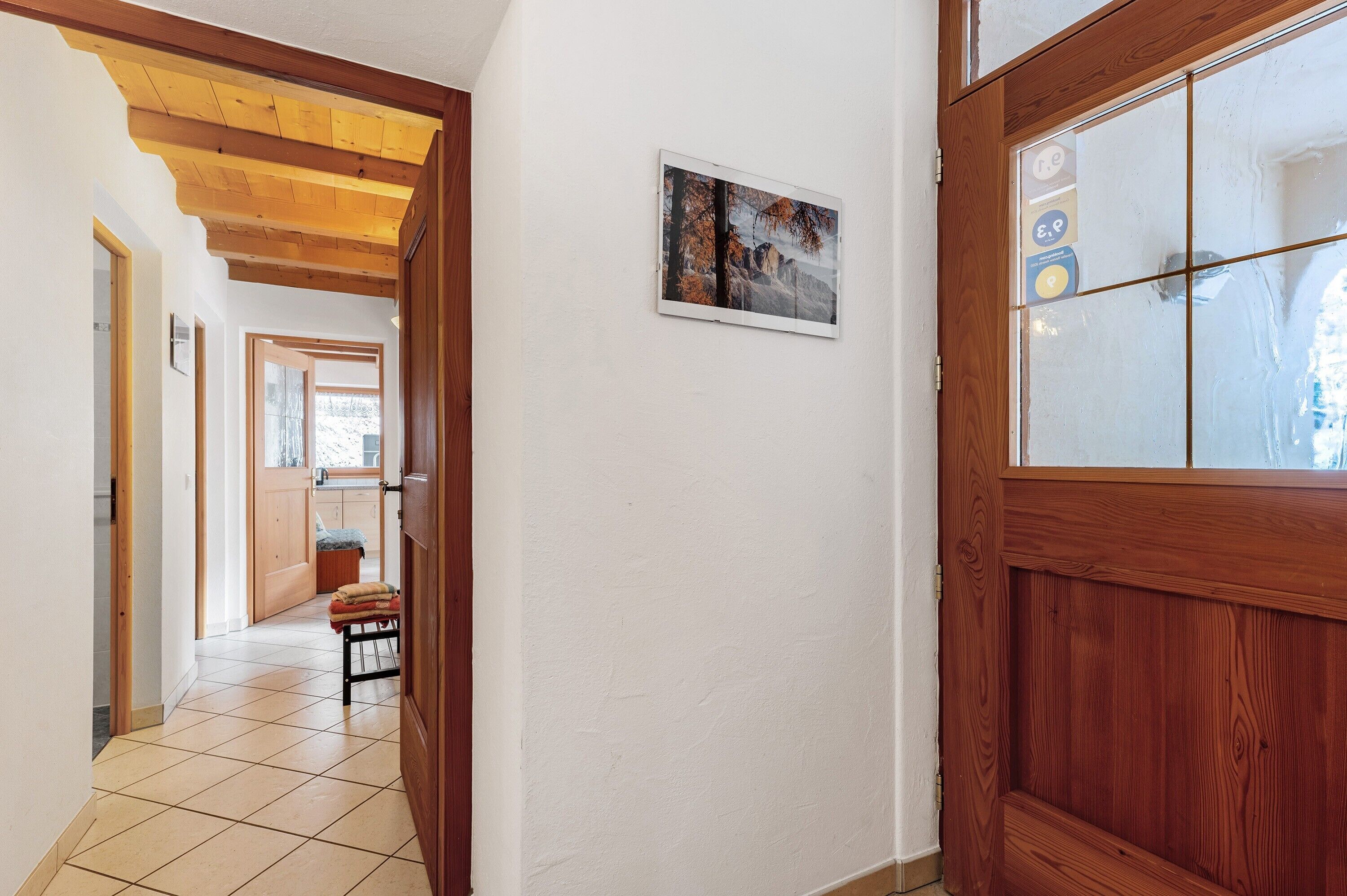 Un pasillo con una puerta de madera, un banco y un cuadro en la pared.