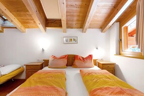 A room with a wooden ceiling, two beds with matching bedding, bedside tables, a window with curtains, and a wall-mounted light fixture. - Apartment 'Heinzenhof  4' with Mountain View, Shared Garden and Wi-Fi (Welschnofen)