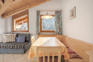 A cozy room with a wooden ceiling, a sofa with plaid cushions, a dining table with a checkered tablecloth, and a window with curtains. - Apartment 'Heinzenhof  2' with Mountain View, Shared Garden and Wi-Fi (Welschnofen)