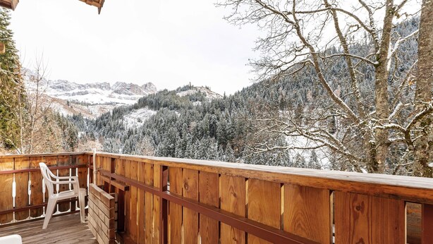 Um deck de madeira com vista para montanhas nevadas e árvores.