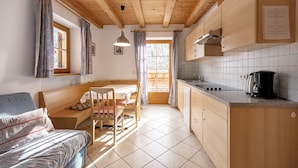 Uma cozinha acolhedora com vigas de madeira, uma área de jantar com banco e vista pela janela.