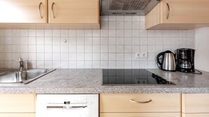 Uma cozinha com pia de aço inoxidável, cafeteira e máquina de lavar louça.