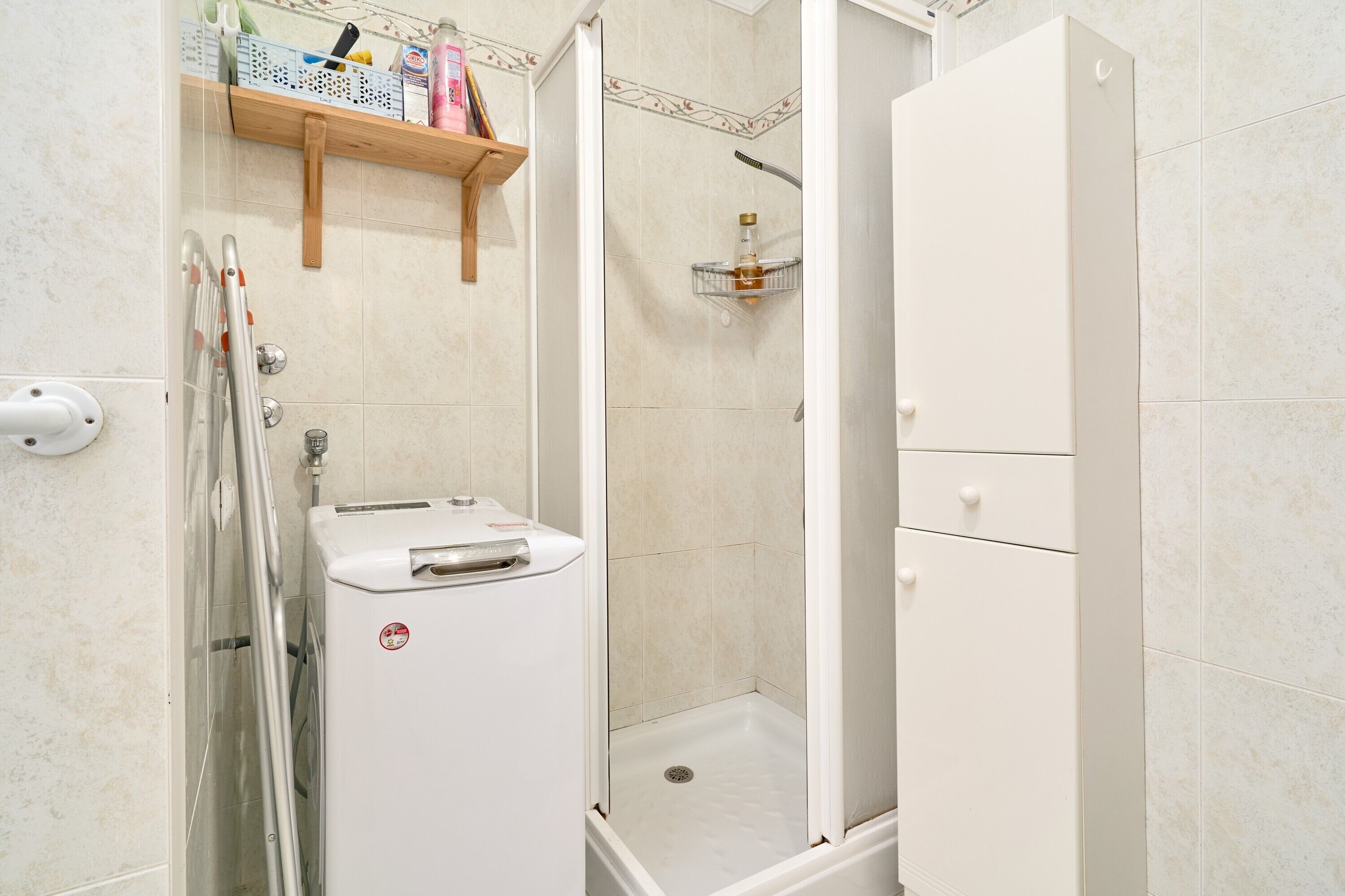 A bathroom with a shower, a toilet, a sink, and a shelf with toiletries.