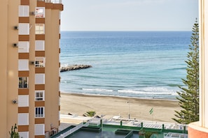 Um edifício alto com varandas dando para a praia e o oceano.