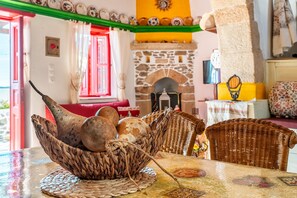 Una habitación con chimenea de piedra, muebles de mimbre y una mesa con mantel tejido.
