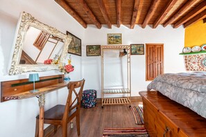 A bedroom with a wooden bed, a desk with a mirror, a chair, a wardrobe, and a shelf with decorative plates. - Holiday Home 'Tis Manas' with Sea View, Private Terrace and Wi-Fi (South Rhodes)