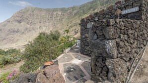 Un bâtiment en pierre avec une enseigne indiquant « EL LAUREL » et un chemin pavé qui monte vers la montagne.