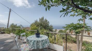 Un patio con un tavolo rotondo, sedie e una pianta in vaso.