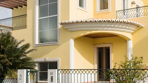 A two-story house with a balcony, a large window, and a door. - Holiday Home 'Laguna Formosa' with Private Terrace, Wi-Fi, SPA/Jacuzzi & Air Conditioning (Faro)