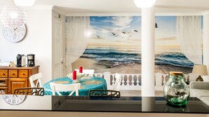 A room with a mural of a beach scene, a dining table with chairs, a clock, and a vase. - Holiday Home 'Laguna Formosa' with Private Terrace, Wi-Fi, SPA/Jacuzzi & Air Conditioning (Faro)