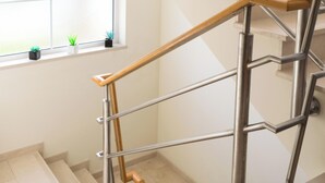 A staircase with a wooden handrail and metal balusters, leading to a landing with a window. - Holiday Home 'Laguna Formosa' with Private Terrace, Wi-Fi, SPA/Jacuzzi & Air Conditioning (Faro)