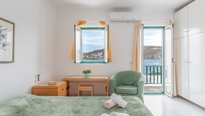 Een slaapkamer met een bed, een bureau, een stoel en een balkon met uitzicht.