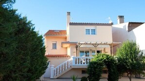 Una casa de dos pisos con un porche cubierto, una escalera visible y un pequeño jardín.